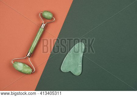 Green Face Jade Roller And Gua Sha Massager Made From Natural Nephritis Stone Over Terracotta Red An