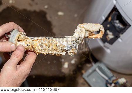Repair And Maintenance Of Boilers. The Master Plumber Took It Out Of The Boiler And Holds In His Han