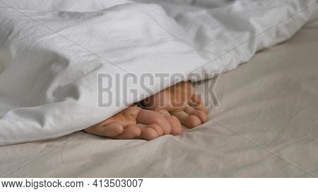 Sleepy Person Covered With Blanket Wriggles Toes In Bed
