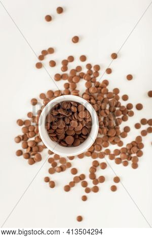 Chocolate In Callets In A White Disposable Cup On A White Background. Home-made Sweets. Top View Clo