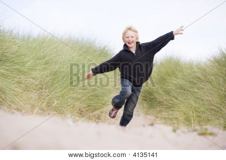Ung dreng kører på stranden smilende