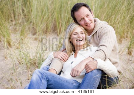 Par sidder på stranden smilende