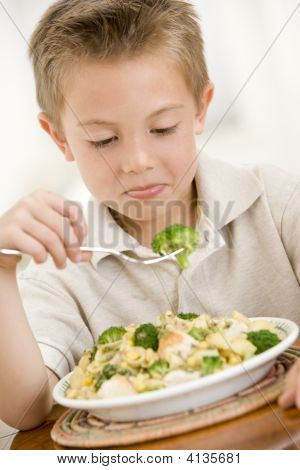 Giovane ragazzo in casa mangiare Pasta con Brocolli
