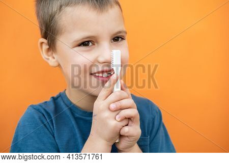 Boy Without Milk Upper Tooth In Blue T-shirt Holds Toothbrush In Hand On The Orange Background.