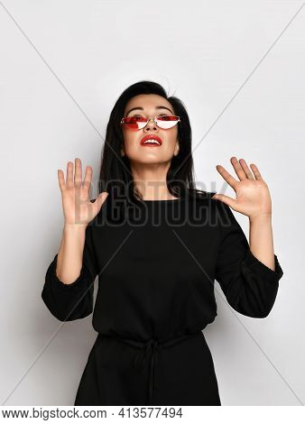 Adult Good Looking Pretty Woman In Stylish Casual Black Dress Stands Holding Hands Up Gesturing Wait