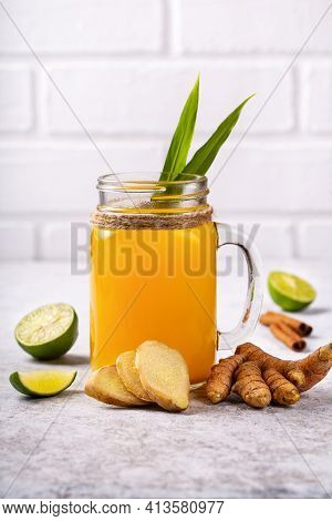 Healthy Drink From Turmeric And Ginger Roots And Lime In A Glass On White Concrete Background. Jamu 