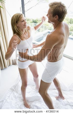 カップルの寝室をジャンプでベッドと笑みを浮かべて