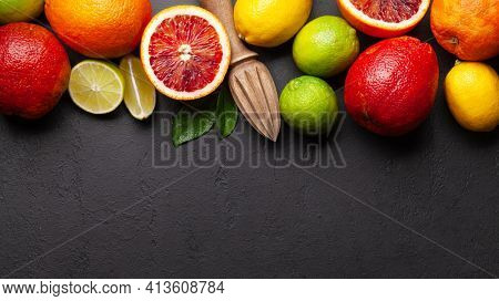 Various fresh citrus fruits and juicer. Bood orange, lime, lemon backdrop. Top view flat lay with copy space