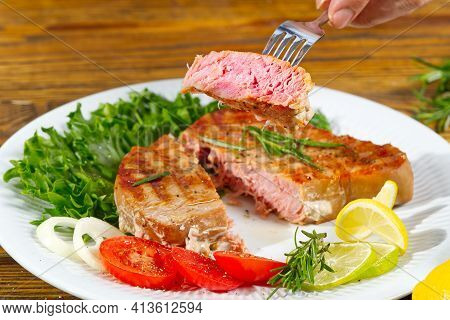 Tuna Steak Cooked On The Electric Grill. Tunafish Served On A Plate With Fresh Herbs And Vegetables.