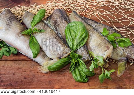Several Raw Carcasses Of The Notothenia Fish Without Of Heads And Tails And Twigs Of Greens  On A Ru