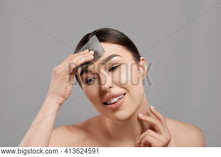 Skin Care. Woman Removing Oil From Face Using Blotting Papers. Closeup Portrait Of Beautiful Healthy