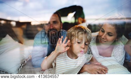 Small Boy With Parents By Window, Holiday In Nature Concept. Shot Through Glass.
