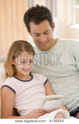 Man och ung flicka i vardagsrummet läsa bok och leende