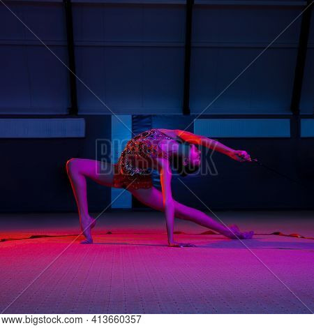 Graceful Caucasian Girl Gymnast Isolated Over Colored Background In Neon Light