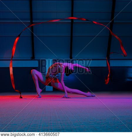 Graceful Caucasian Girl Gymnast Isolated Over Colored Background In Neon Light
