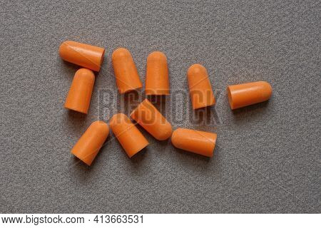 Heap Of Red Plastic Earplugs On A Gray Table
