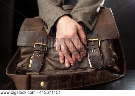 Teachers Hands Are On An Old Leather Briefcase With Metal Buckles On The Table.
