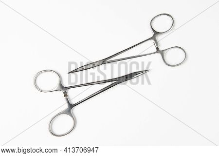 Two Surgical Clamps Lie Opposite Each Other Isolated On White Background