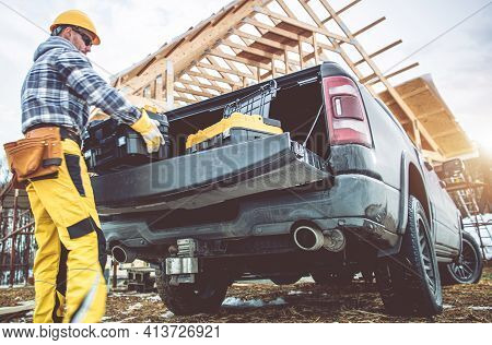 Caucasian Construction Contractor Worker In His 40s Taking Tools Boxes From Bed Section Of His Picku