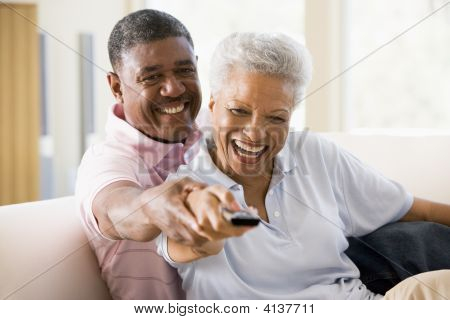 Coppie nel salotto utilizzando il telecomando sorridente