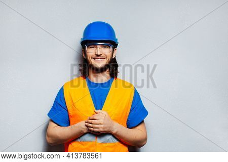 Studio Portrait Of Young Happy Construction Worker Engineer On The Background Of Grey Wall. Wearing 