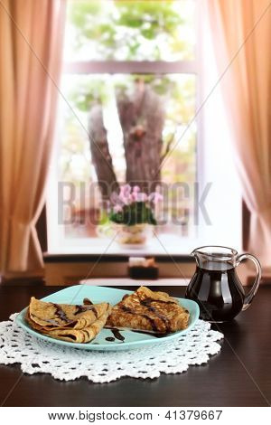 หวาน pancakes บนแผ่นกับนมข้นบนโต๊ะในห้อง