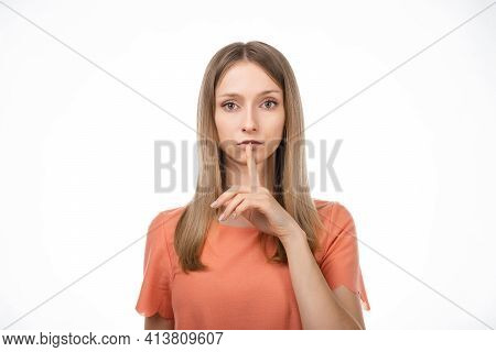 Portrait Of Young Blond Woman Keeping Finger At Her Mouth, Saying Shh, Hush, Tsss. Silence And Secre