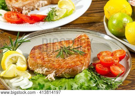 Tuna Steak Cooked On The Electric Grill. Tunafish Served On A Plate With Fresh Herbs And Vegetables.