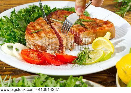 Tuna Steak Cooked On The Electric Grill. Tunafish Served On A Plate With Fresh Herbs And Vegetables.
