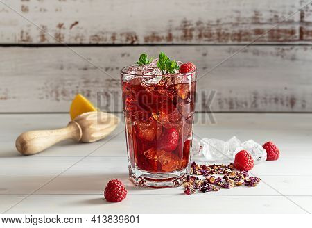 Hibiscus Ice Tea Or Karkade Lemonade With Raspberries, Mint, And Lemon On A Wooden Table.
