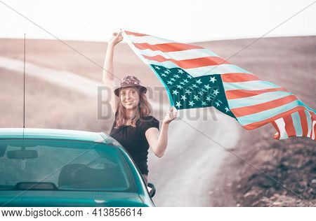 Young woman holding waving American USA flag. Independence Day or traveling in America concept.