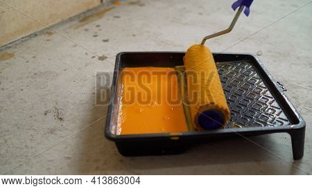 Orange Putty And Roller In The Tray. Putty, Tray And Roller. Paint Roller, Tray With Orange Paint On