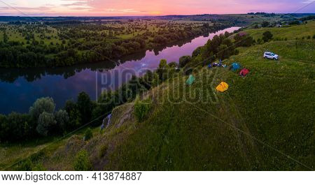 Group of tourists camping on the coast of the river of Sylva in Perm Kray in Russia during colorful pink sunset