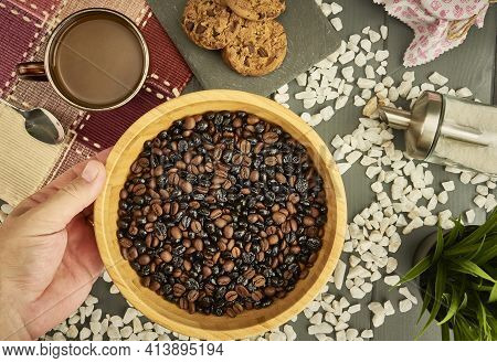 Mix Of Natural And Roasted Coffee In A Bowl Held By A Caucasian Hand On Wooden Table With Cookies, C