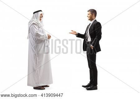 Full length profile shot of a young businessman talking to a mature arab man in a traditional thobe isolated on white background