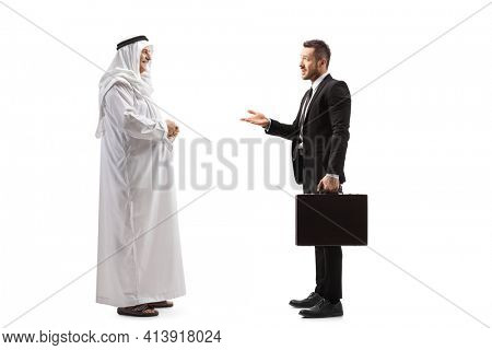 Full length profile shot of a businessman talking to an arab man in a traditional thobe isolated on white background