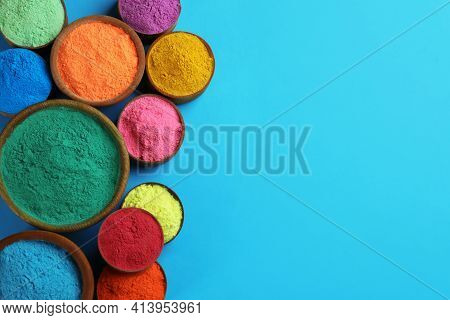 Colorful Powders In Bowls On Light Blue Background, Flat Lay With Space For Text. Holi Festival Cele