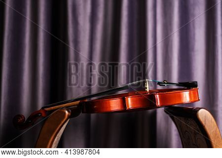 Beautiful Violin With Tense Strings On Purple Curtain Background. Composition Of Musician Working Eq