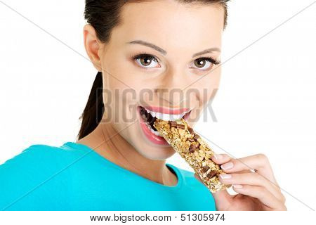 Jovem mulher comer barra de Cereal chocolate, isolada no branco