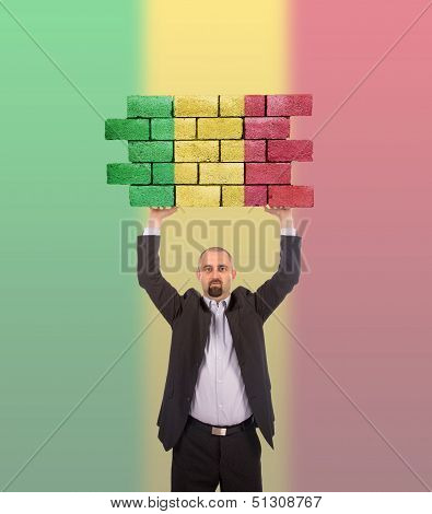 Businessman Holding A Large Piece Of A Brick Wall