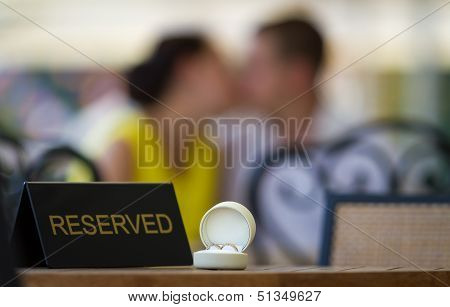 Wedding Rings On A Table And Kissing Couple