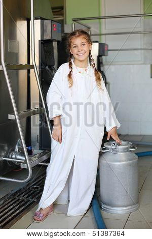 Happy beautiful girl in white coat stands with big aluminum can of milk.