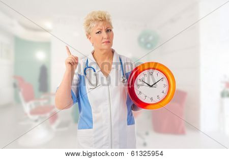 Mature nurse with clock at medical office