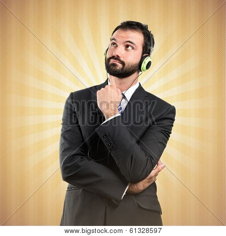 Young Businessman Listening Music Over Ocher Background