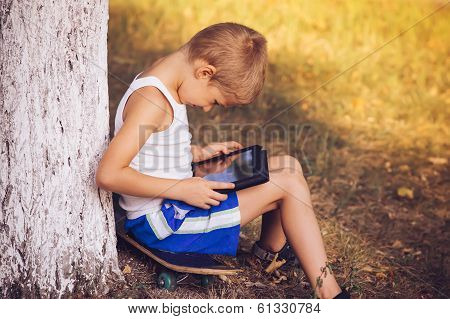 Boy Child Playing With Tablet Pc Outdoor With Summer Nature On Background Computer Game Dependence C