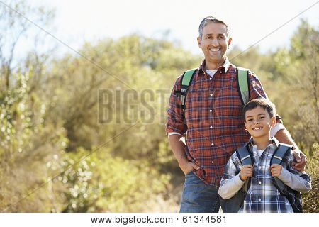 Father And Son Hiking In Countryside Wearing Backpacks