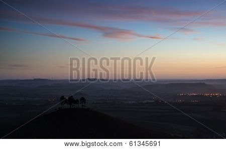 Beautiful Sunrise Dawn Landscape Of Hills Overlooking Brightly Lit Town In Valley Below