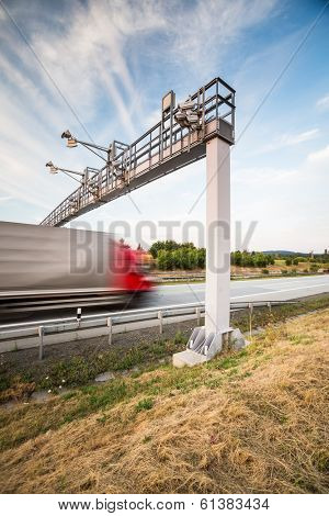 truck passing through a toll gate on a highway (motion blurred image; color toned image)