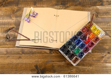 Composition with colorful watercolors, brushes and sketcher on wooden background 
