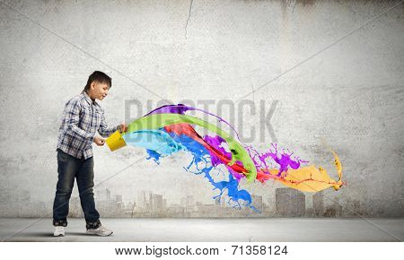 Young boy splashing colorful paint from bucket